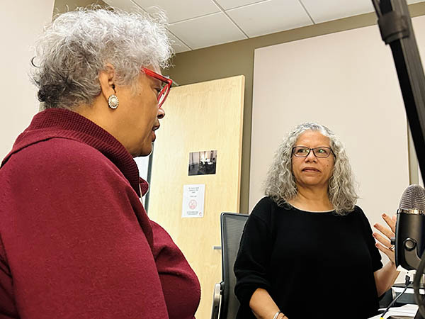 Carmen Foster and Ana Edwards having a conversation in a recording booth