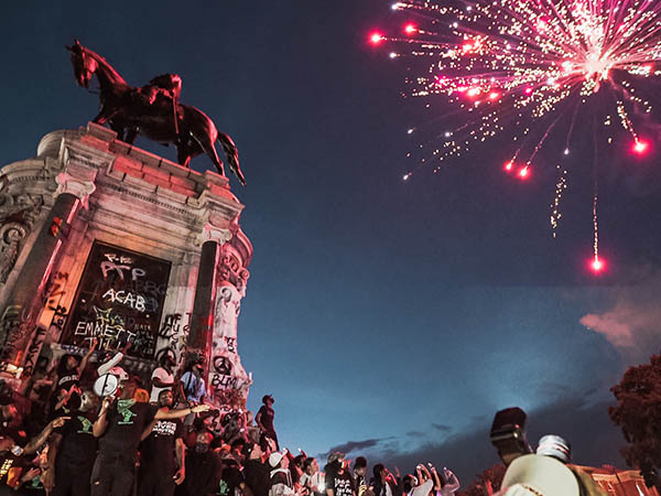 Graffitied Robert E. Lee statue in Richmond surrounded by protesters